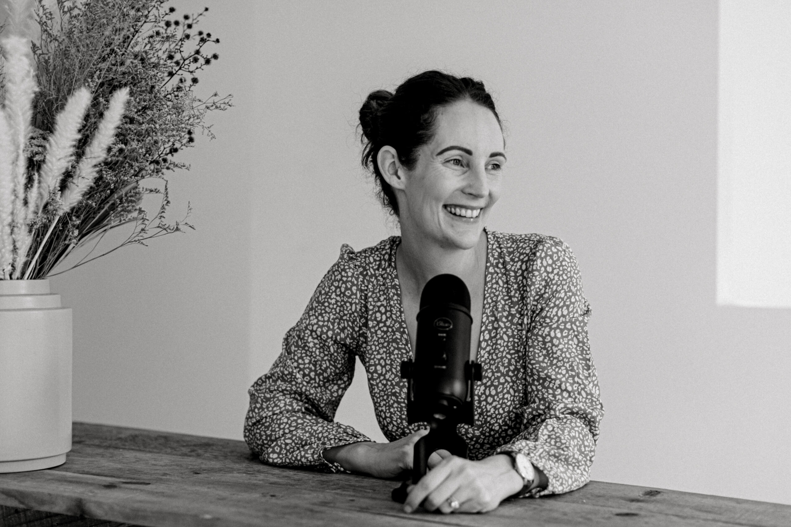 black and white photo of a woman sitting at a desk with a podcast mic