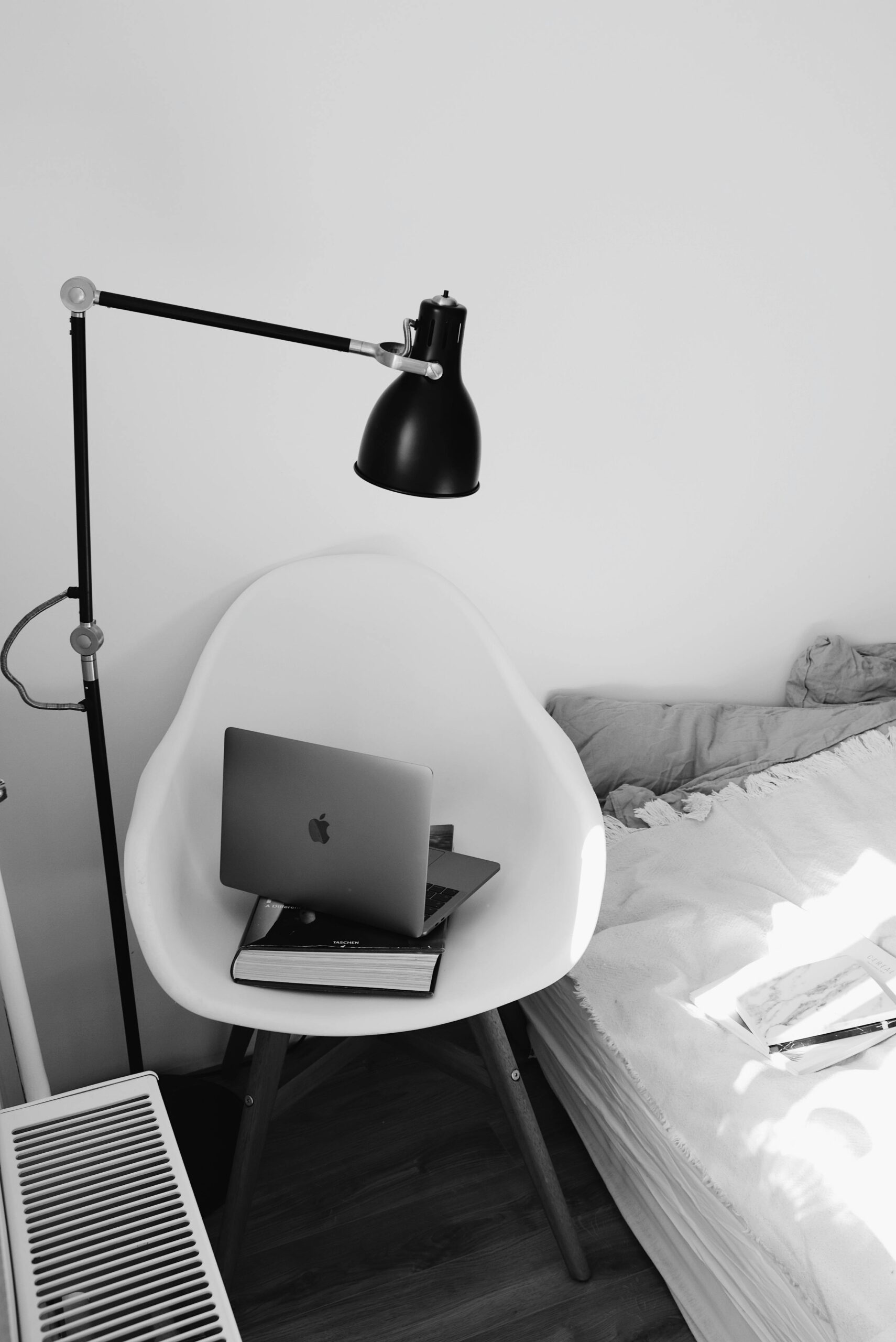 black and white photo of a laptop on a chair next to a bed